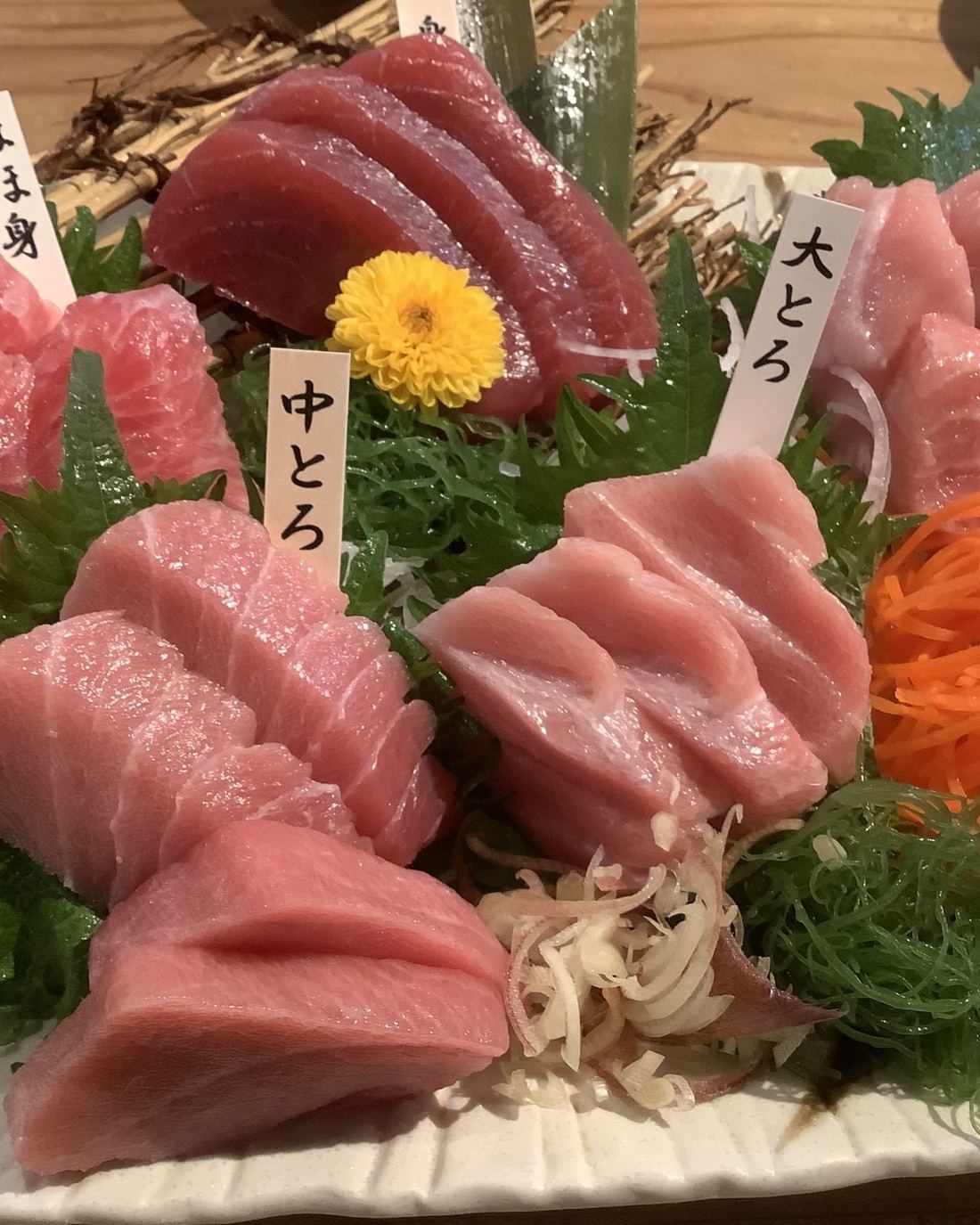 Sashimi de atún, toro y chutoro sobre hielo, con etiquetas escritas a mano