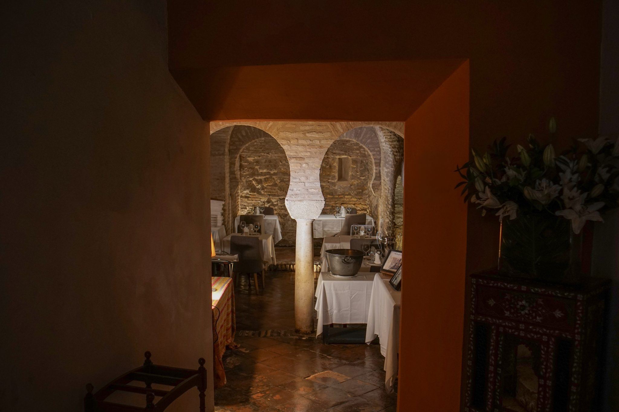 Comedor en penumbra visto a través de arcos de herradura
